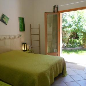 - une chambre avec un lit vert et une porte coulissante en verre dans l'établissement Louminai, à Donzère