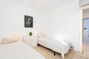 a white bedroom with two beds and a chair at Torremuelle - Apartment with private pool & BBQ in Benalmadena in Benalmádena
