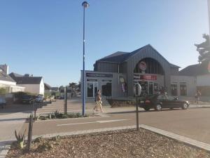 une femme marchant dans une rue devant un bâtiment dans l'établissement Le Courlis, à deux minutes de la plage, à Hauteville-sur-Mer