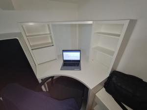 a laptop computer sitting on a white desk with shelves at La Mansarda di Cremona in Cremona