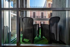 deux chaises assises sur un balcon regardant par une fenêtre dans l'établissement Dante 138 Class rooms & apartments, à Bari