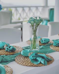 a table with blue napkins and a vase with flowers at Bay House Grenada in Belmont