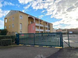 a building with a green gate in front of it at Appartement Marseillan-Plage, 4 pièces, 6 personnes - FR-1-387-164 in Marseillan