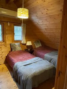 dwa łóżka w pokoju w drewnianym domku w obiekcie 919KOBE ARIMA w mieście Kobe