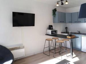 una cucina con 3 sgabelli da bar e una TV a parete di Studio Les Orres, 1 pièce, 4 personnes - FR-1-322-479 a Les Orres