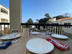 een tafel met witte borden en wijnglazen op een balkon bij Appartement Dolus-d'Oléron, 2 pièces, 4 personnes - FR-1-246A-182 in Dolus d'Oléron