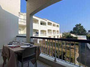 stół na balkonie z widokiem na budynek w obiekcie Appartement 2 pièces avec balcon, piscine, proche plage à Dolus-d'Oléron - 4 couchages - FR-1-246A-182 w mieście Dolus d'Oléron