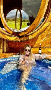 a woman in a swimming pool with a glass of wine at Complejo turístico Magic Bungalow in Villa de Leyva