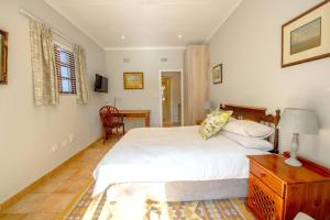 um quarto com uma cama branca e uma cómoda em madeira em Power Backup, Parkwood 10min Walk to Rosebank em Joanesburgo