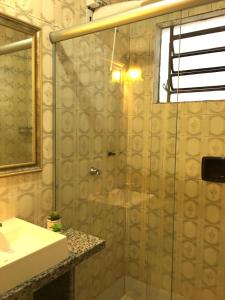 een badkamer met een douche, een wastafel en een spiegel bij Nossa Casa Novo Hamburgo in Novo Hamburgo
