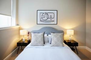 1 dormitorio con 1 cama blanca grande y 2 lámparas en The Waltham Forest Escape - Adorable 2BDR Flat en Londres