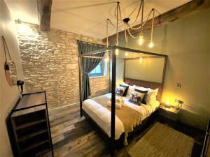 - une chambre avec un lit à baldaquin et un mur en briques dans l'établissement Marske Stables, Yorkshire Dales, à Marske