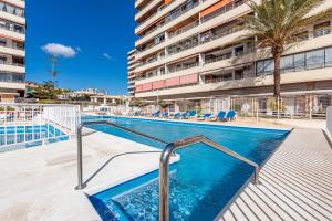 a swimming pool in front of a building at La Nogalera - Sea view apartment in the heart of Torremolinos in Torremolinos