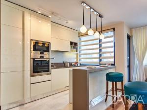 a kitchen with white cabinets and a blue stool at Apartment Braila in Plovdiv