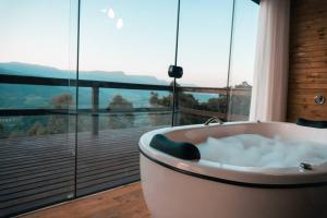 a bath tub in a room with a large window at Cabanas nos Canyons in Praia Grande