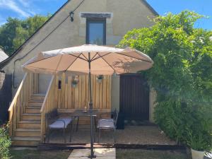 a table and chairs under an umbrella in front of a house at L'éloge de Vouvray, Orbois in Vouvray