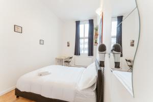a white bedroom with a bed and a mirror at Bethnal Green beds to stay in London