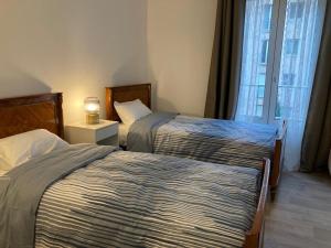 2 bedden in een hotelkamer met een raam bij Appartement entier avec parking gratuit proche de Paris et Aéroport d'Orly in Thiais