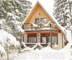 a log cabin in the snow with the words ski to door at Traveland Alpina Resort Poiana Brasov in Poiana Brasov