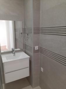 a white bathroom with a sink and a mirror at Casa da Travessa II in Ponte de Lima