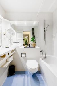 e bagno bianco con servizi igienici, lavandino e vasca. di Luganersee, Pool, Strand, Parkplatz, Suite 204 a Bissone
