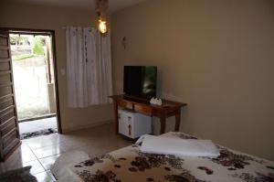 - une chambre avec un lit et une télévision sur une table dans l'établissement Sítio Vale da Serra, à Maranguape