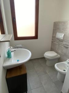 a bathroom with a white sink and a toilet at Il Sole Verde in Marrùbiu