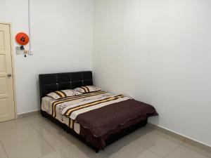 Cama en habitación con pared blanca en De Pontian Homestay, en Pontian Besar