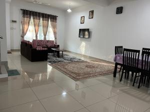 a living room with a couch and a table and chairs at De Pontian Homestay in Pontian Besar