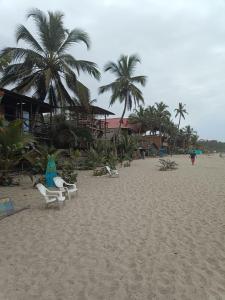una playa de arena con sillas y palmeras. en Bob Marley Beach en Guachaca