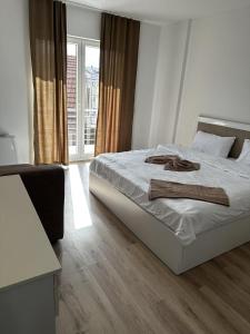 um quarto com uma cama com lençóis brancos e uma janela em Vila Andrra em Struga