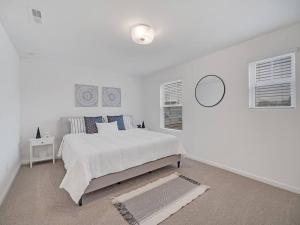 a white bedroom with a bed and a mirror at Gorgeous New Townhome/Charlotte! in Charlotte