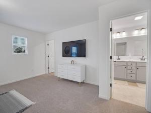 ein weißes Badezimmer mit einem Waschbecken und einem TV in der Unterkunft Gorgeous New Townhome/Charlotte! in Charlotte