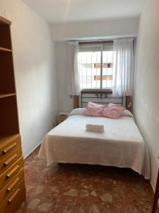 Un dormitorio con una cama con almohadas rosas y una ventana en Descans, en Cullera