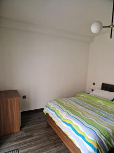 una camera da letto con un letto con una coperta colorata a righe di The Clover a San Pawl il-Baħar