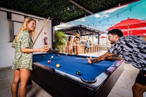 een man en een vrouw die pool spelen op een pooltafel bij Nomads Party Hostel in Cancun