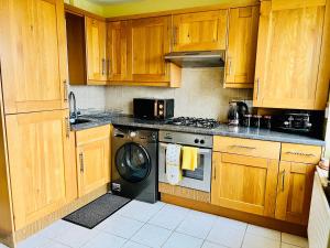 a kitchen with wooden cabinets and a washing machine at Sunset House On The Beach in Maryport