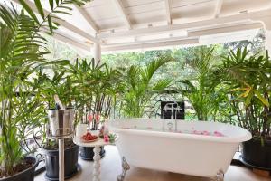 bañera en una habitación con plantas en Mademoiselle Boutique Resort and Cafe, en Vagator