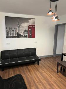 sala de estar con sofá negro y cabina de teléfono en Kensington Stories - 4 Bed House en Watford