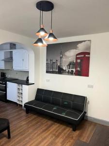 a black couch in a living room with a kitchen at Kensington Stories - 4 Bed House in Watford