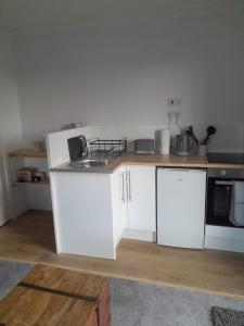 una cocina con armarios blancos y fregadero en Lealt Falls Apartment en Culnacnoc