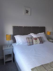 a bedroom with a white bed with pillows and two lamps at Lealt Falls Apartment in Culnacnoc