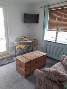 salon ze stołem i biurkiem z telewizorem w obiekcie Lealt Falls Apartment w mieście Culnacnoc