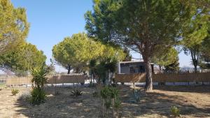 une maison dans une cour avec des arbres et une clôture dans l'établissement Domaine de L'Outarde Canepetiére Gîte A, à Aigues-Mortes