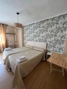 1 dormitorio con 2 camas y pared con papel pintado en Hosteria Tajahierro, en Reinosa