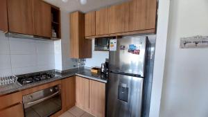 a kitchen with a stainless steel refrigerator and wooden cabinets at Bellisimo departamento en el Tabo in El Tabo