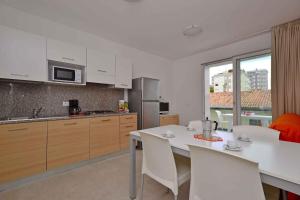a kitchen with a white table and white chairs at Apartments in Lignano 21707 in Lignano Sabbiadoro