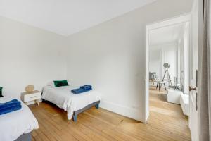 una camera bianca con 2 letti e uno specchio di 2 bedrooms center of Clichy ! a Clichy