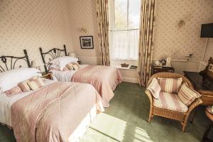 1 dormitorio con 2 camas, silla y ventana en The Old Rectory, en Coniston