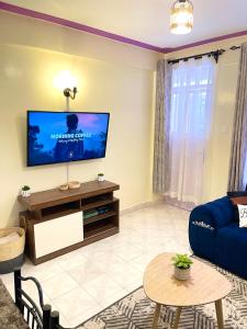 a living room with a tv and a blue couch at Cosy and spacious apartment in Meru in Meru